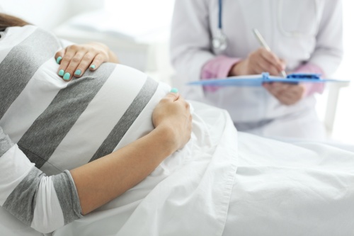 ベッドの上で横たわる妊婦